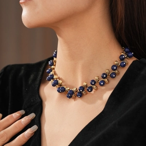 Detail of vintage gold metal necklace with woven blue beads and silver accents