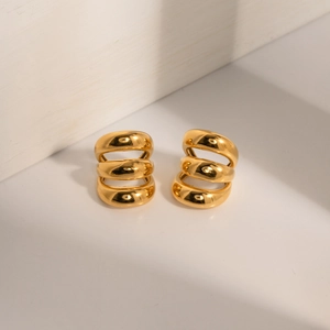 Detailed close-up of triple-layered gold-plated stainless steel ear cuffs on a white base