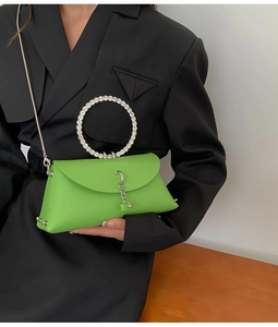 Detail of green crossbody bag featuring a sparkling crystal handle and silver chain strap