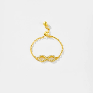 Detailed macro view of the gold infinity symbol ring with zircon pavé and pull chain