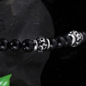 Detail of black beads necklace with silver star engraved spacer on stone and leaf