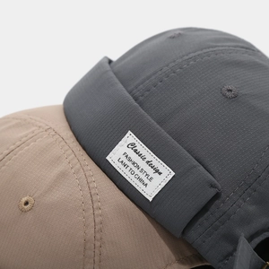 Détail du tissu ripstop à séchage rapide et étiquette sur les bonnets kaki et gris sans bord