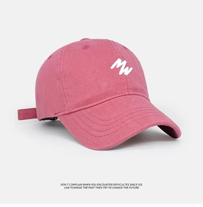 Detail of pink washed cotton baseball cap featuring embroidered MW logo and soft vintage texture