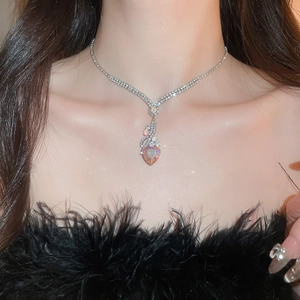 Close-up of heart-shaped crystal pendant necklace worn by a model in black attire