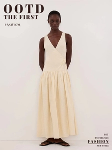 Détail d'une robe en coton crème à col en V avec ceinture nouée et tissu texturé