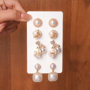 Detail of four sets of faux pearl earrings with rhinestones on a gold alloy base
