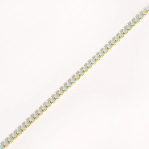Detail of gold chain with light blue round stones in a single-row claw setting style