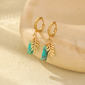 Detail of gold clover leaf and turquoise natural stone charms on stainless steel earrings