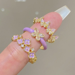 Macro shot of gold-plated rings with purple enamel butterfly motifs and zircon stones