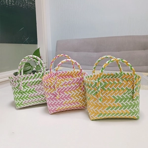 Detailed view of three handcrafted woven tote baskets in pastel green, pink, and yellow colors