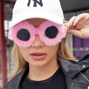 Detail of pink plush fur frame sunglasses with round dark lenses worn by a model
