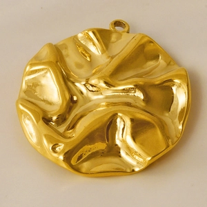 Vue macro d'un pendentif circulaire en acier doré avec texture froissée unique
