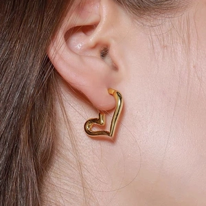 Close-up of elegant gold heart-shaped earrings worn by a model for a stylish vintage look