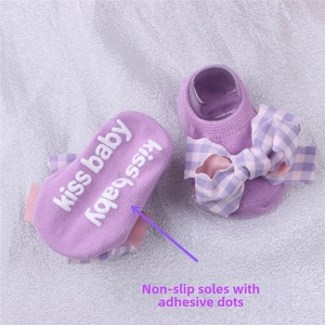 Detail of purple baby socks featuring pink plaid bow and anti-slip rubber lettering