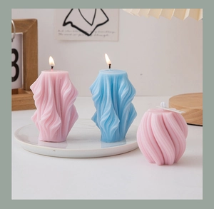 Artistic pastel geometric candles in pink and blue shades set on a white desktop