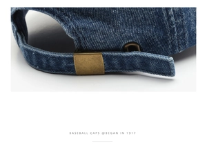 Macro shot of dark blue denim baseball cap showing adjustable strap and brass buckle