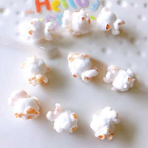 Flat lay macro of nine realistic white resin popcorn charms for DIY jewelry making