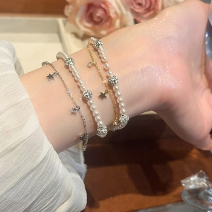 Detail of layered bracelets featuring pearls, zircon stars, and delicate gold and silver chains
