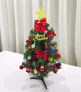 Detail view of mini green Christmas tree with golden star and festive ornaments