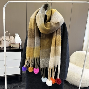 Rainbow plaid scarf in yellow and brown tones with colorful pom-pom tassels on display
