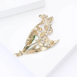Detailed back view of a golden flower brooch with green enamel leaf and secure pin fastener