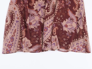 Detailed view of bohemian paisley print chiffon hem in deep burgundy and purple tones