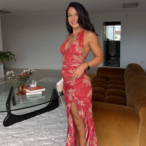 Détail de robe longue fleurie rouge à dos nu avec découpe à la taille et fente latérale