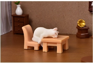 Miniature resin cat sleeping on a tiny chair and table set for micro landscape decor