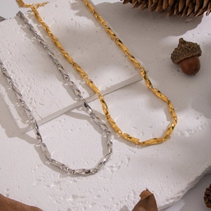 Gold and silver geometric chain necklaces displayed with natural pine cones decor