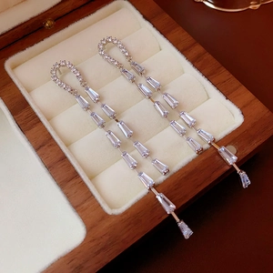 Close-up of long U-shaped tassel earrings with silver finish and sparkling cubic zirconia