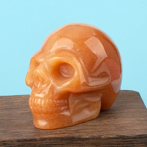 Macro shot of polished orange crystal skull carving on a dark wood display base