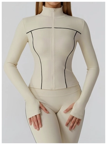 Detailed close-up of beige athletic zip jacket featuring black contrast stitching and thumbholes