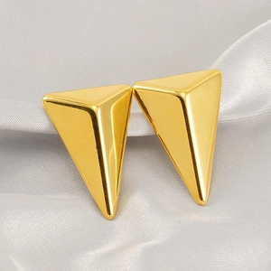 Detailed view of polished 18K gold triangle stud earrings on soft grey silk fabric