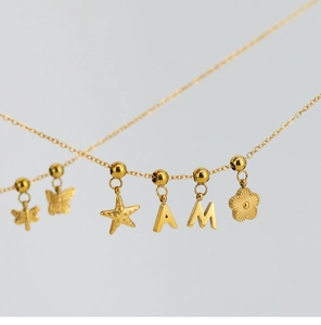 Close-up of golden stainless steel necklace with butterfly, dragonfly and star charms