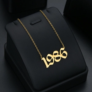 Detailed close-up of golden stainless steel 1986 year pendant on a black jewelry stand