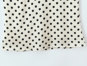 Detailed close-up showing soft polka dot fabric texture and hem stitching on the dress