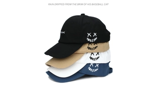 Details von vier bunten Baumwoll-Basecaps mit gestickten XX-Smiley-Gesichtsmustern