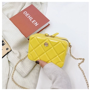 Close-up of yellow quilted jelly bag featuring a gold flower clasp and metal chain strap