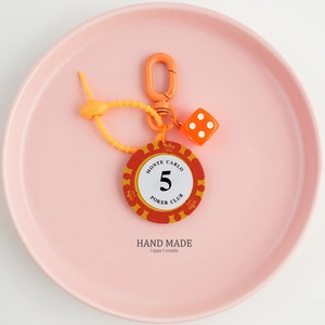 Close-up of orange poker chip keychain with Monte Carlo 5 token and matching dice pendant