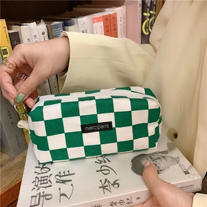 Detailed view of the green checkered canvas pencil case with a black brand tag