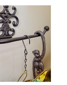 Detail of vintage cast iron monkey hook with rustic texture and stained glass ornament
