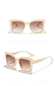 Detail view of oversized square cat-eye sunglasses with cream frames and gradient lenses