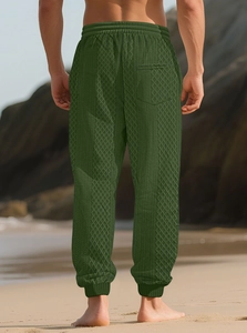 Détail du pantalon jogging vert homme avec texture jacquard en losange sur la plage