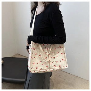 Detail view of large cream canvas tote bag with cherry prints and adjustable strap