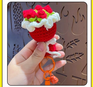 Detail of handmade crochet red rose keychain with bell and green leaf accents