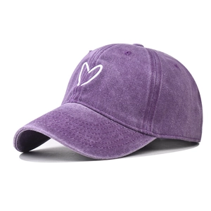 Detailed close-up of the white heart embroidery on a purple washed cotton baseball cap