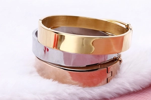 Detailed view of wide stainless steel bangles in gold, silver, and rose gold with stones