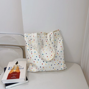 Detail of a white canvas tote bag with colorful polka dots and a fabric label on the front