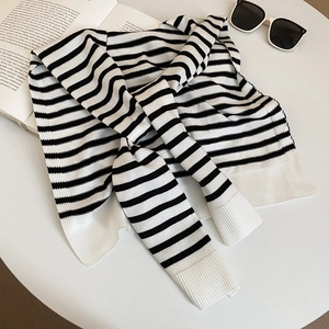 Detail of black and white striped knit shawl featuring wide ribbed cuffs and texture