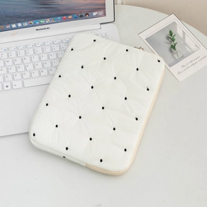 Detail of white quilted laptop sleeve with black dot pattern and premium beige zipper
